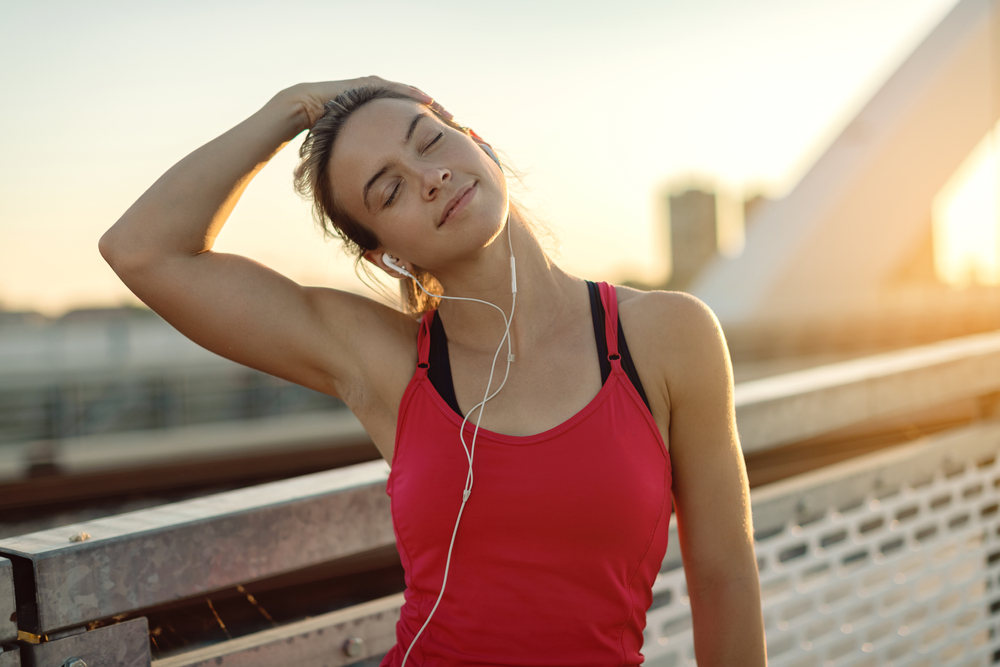 Smiling, athletic couple jogging in a sunny, forested area, enjoying an energetic workout in nature - Butler Spine & Sport