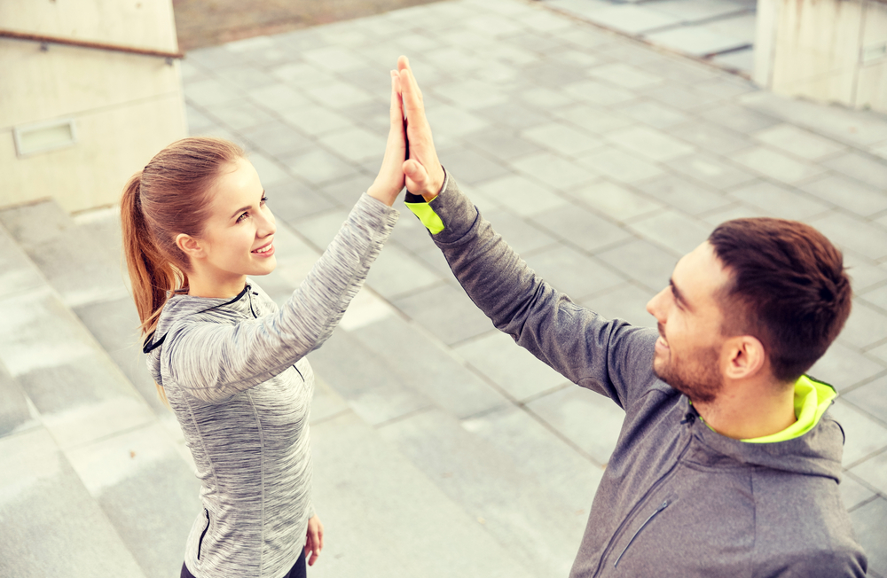 Smiling, athletic couple jogging in a sunny, forested area, enjoying an energetic workout in nature - Butler Spine & Sport